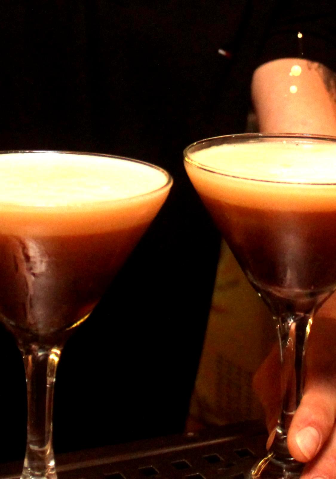 Two Espresso Martini cocktails with thick crema foam in martini glasses being served at The Garden Bar & Kitchen, Kardamena, Kos.